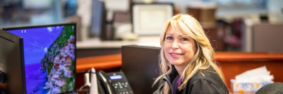 Customer Service Representative sitting at a computer and smiling at the camera.