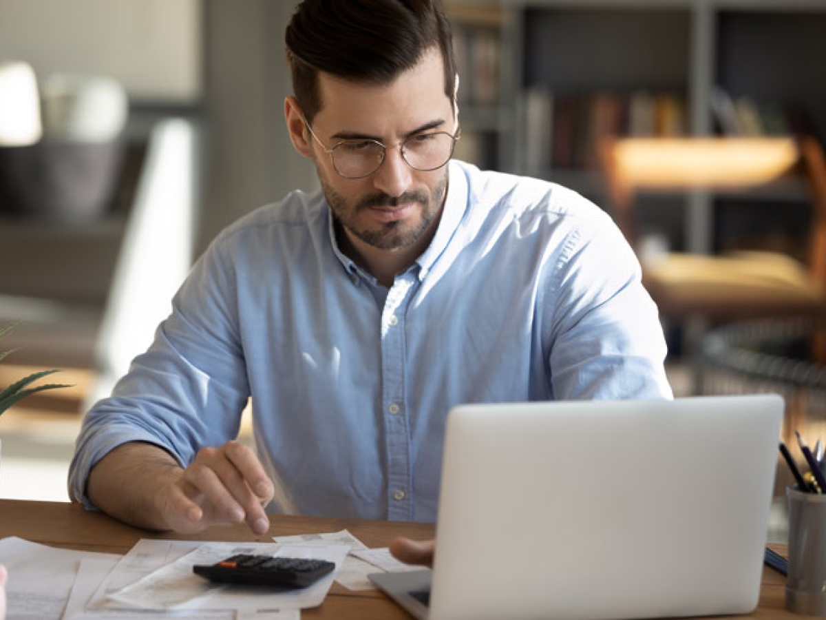 Man sitting in front of his computer with a calculator